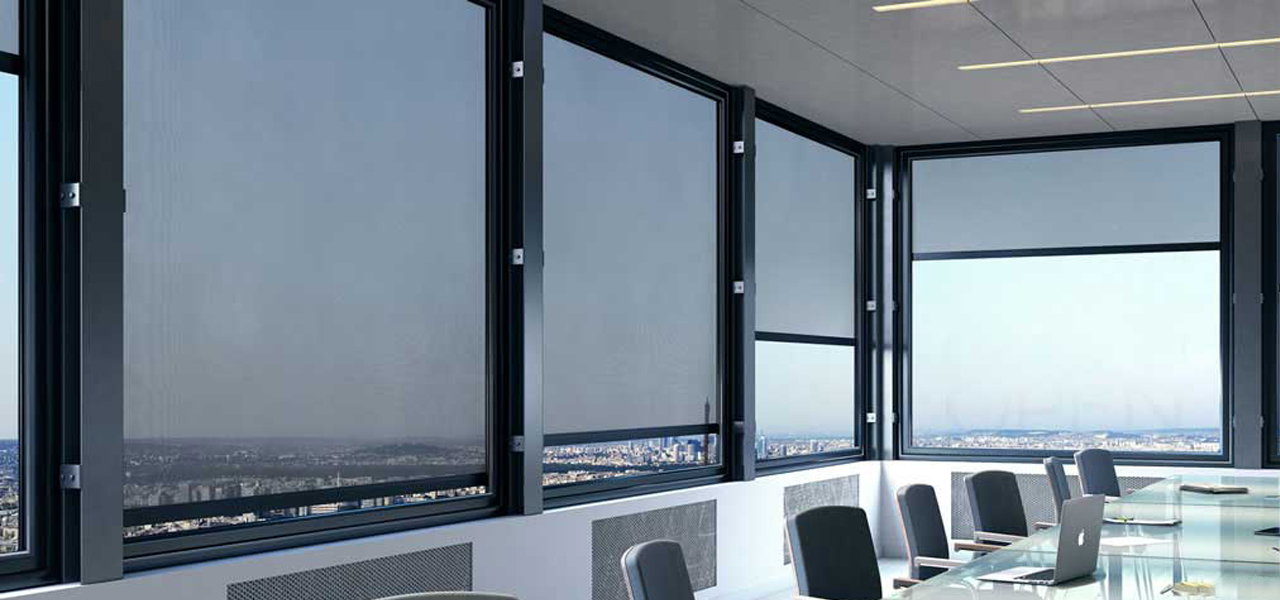 Angle salle de réunion dans un immeuble. Les fenêtres sont protégées par des stores films, verticaux guidés de couleur noire.